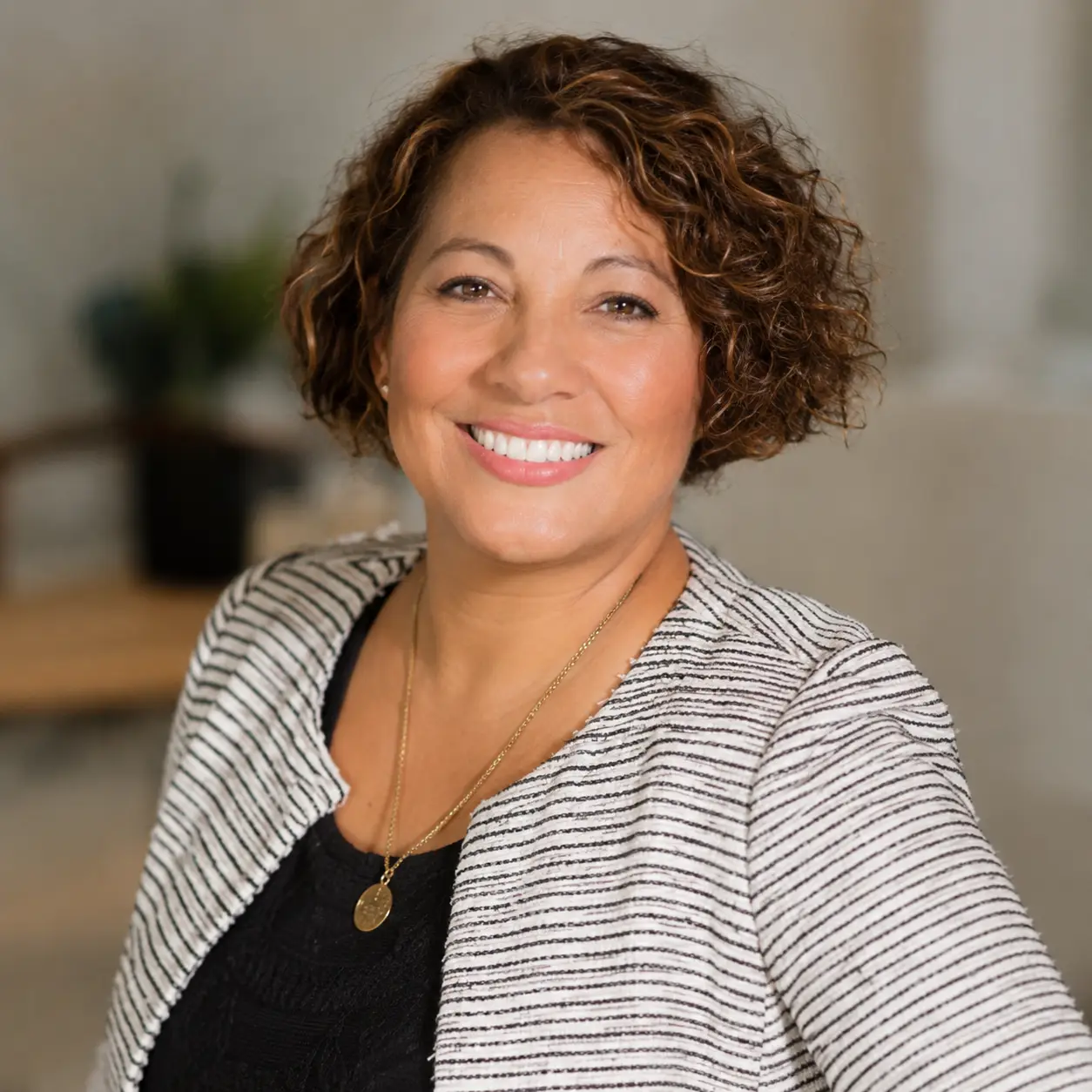 Middle aged Aboriginal Woman in striped blazer smiling at the camera